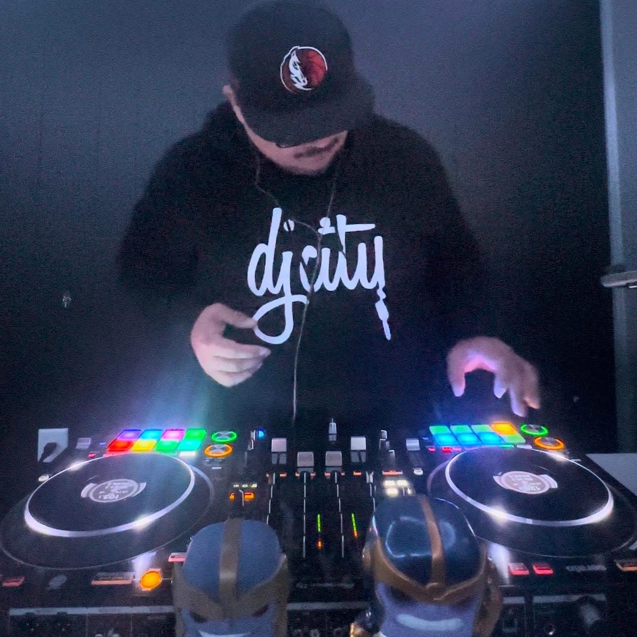 DJ John Styles mixing on turntables wearing DJ City hoodie