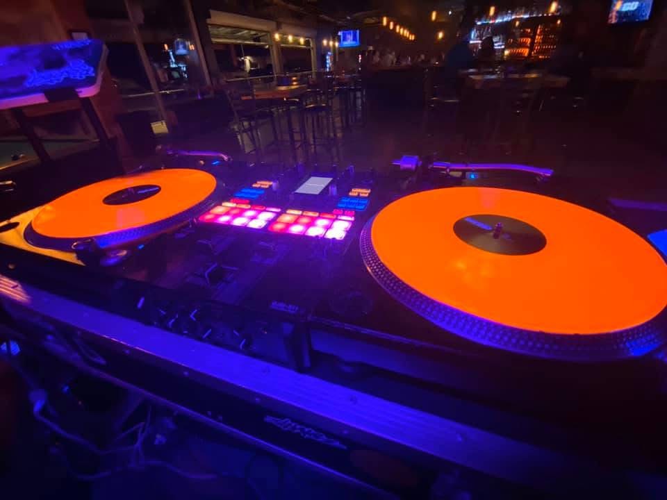 Turntables with glowing orange vinyl under neon lights